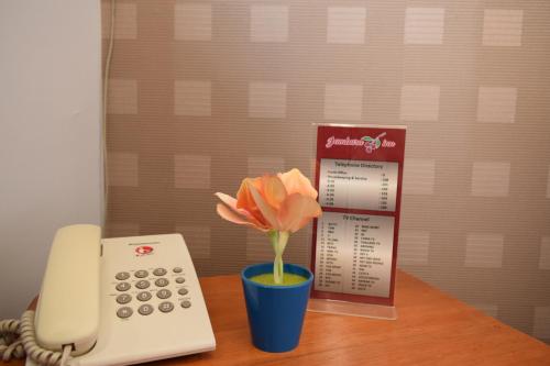 a phone and a vase with a flower on a table at Jambura Inn in Gorontalo