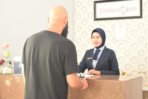 a man standing at a counter with a woman at Jambura Inn in Gorontalo