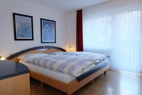 a bedroom with a bed and a large window at Artist Apartments & Hotel Garni in Zermatt