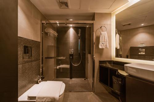a bathroom with a shower and a toilet and a sink at Ambara Suites in Trivandrum