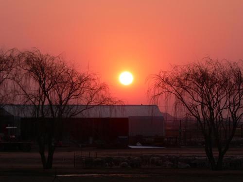 a sunset over a barn with the sun in the sky at Nations Lodge in Lynchfield
