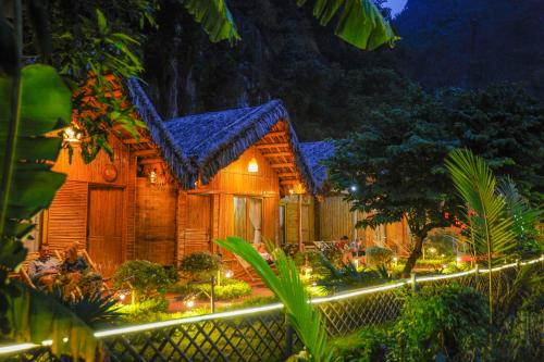 a wooden house with lights in a garden at night at Tam Coc Horizon Bungalow in Ninh Binh