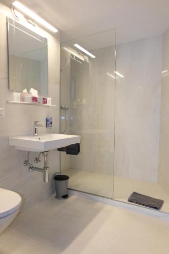 a bathroom with a sink and a glass shower at Artist Apartments & Hotel Garni in Zermatt