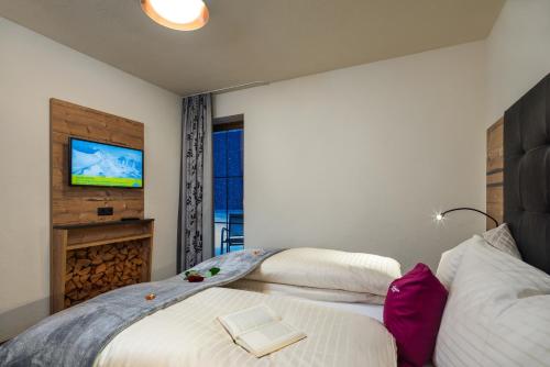 a bedroom with two beds and a tv on the wall at Alpin Chalet am Burgsee in Ladis