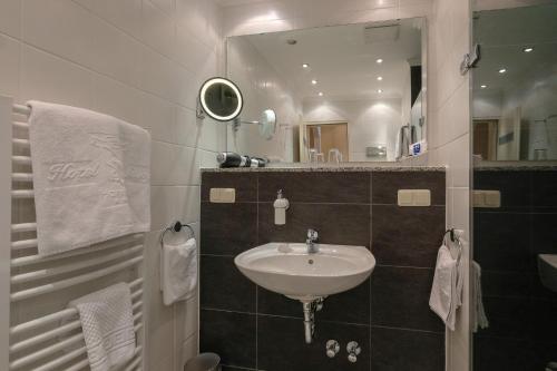 a bathroom with a sink and a mirror at Hotel Savoy Hannover in Hannover