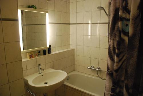 La salle de bains est pourvue d'un lavabo, d'une baignoire et d'un miroir. dans l'établissement Arkonablick 53, à Juliusruh