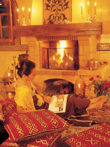 a woman sitting on a bed in front of a fireplace at Rive Du Lac in Lalla Takerkoust