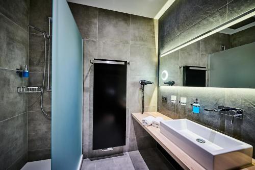 a bathroom with a sink and a shower and a mirror at Posthotel Walhalla Regensburg Ost in Donaustauf