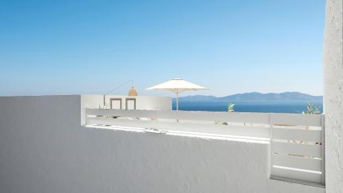 a white fence with an umbrella and the ocean at Living Theros Luxury Suites in Kardiani