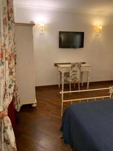 Habitación con mesa y TV en la pared. en Dimora Caracciolo, en Nápoles