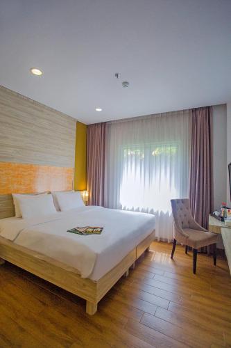 a bedroom with a bed and a chair and a window at Front One Akshaya Hotel Karawang in Karawang