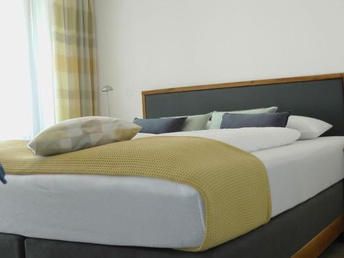 ein großes Bett mit weißen und blauen Kissen darauf in der Unterkunft Maisonette am See in Nonnenhorn