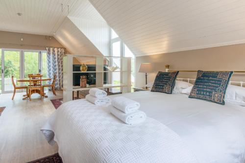 a bedroom with a large bed with towels on it at The Coach House at Hillwood in Cape Town