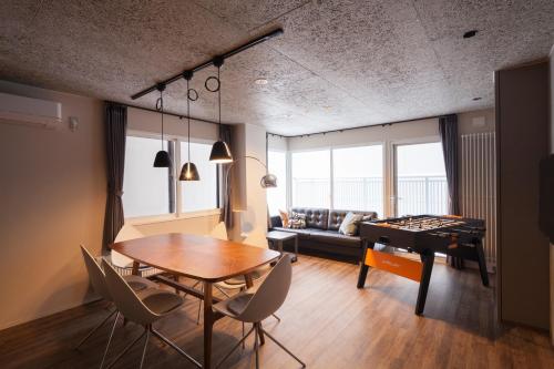 Private house Kuranoya Sapporo في سابورو: غرفة معيشة مع طاولة بينج بونغ وغرفة معيشة مع أريكة
