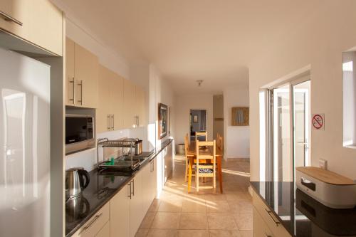 a kitchen with white cabinets and a dining room at Infinity Blue Luxury Accommodation in Wilderness