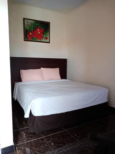 a bedroom with a bed with white sheets and pink pillows at Villadevi in Pangandaran