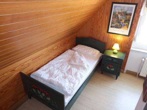 a small bed in a room with a wooden wall at Strandmensch Dornumersiel in Dornum