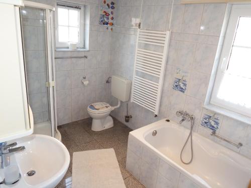 a bathroom with a tub and a toilet and a sink at Strandmensch Dornumersiel in Dornum