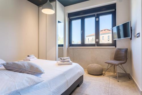 um quarto com uma cama, uma cadeira e uma janela em New Apartment ParkView/CityView em Split