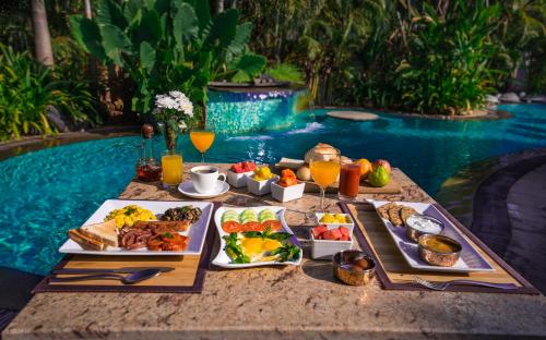 a table with food and drinks next to a pool at Fiesta Beach Resort in Baga