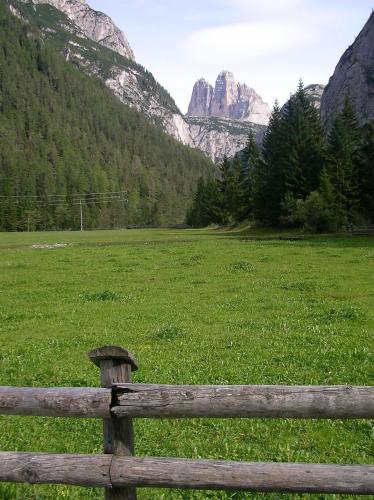 a wooden fence in a field with mountains in the background at Hotel Waldheim in Valle Di Casies