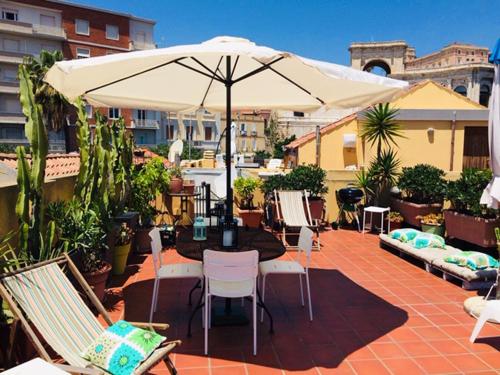 um pátio com uma mesa, cadeiras e um guarda-sol em B&B St. Remy em Cagliari