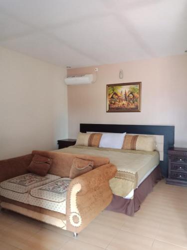 a bedroom with a bed and a couch in it at Villadevi in Pangandaran