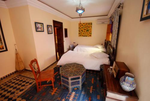 a bedroom with two beds and a table and a chair at Rive Du Lac in Lalla Takerkoust
