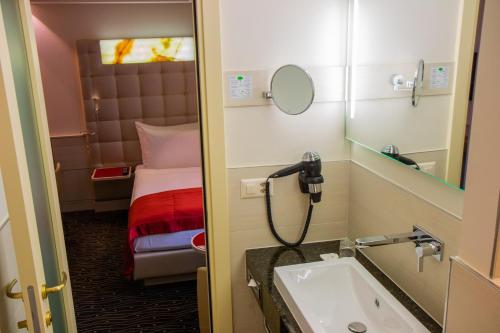 a small bathroom with a sink and a bed at Hotel St.Gotthard in Zurich