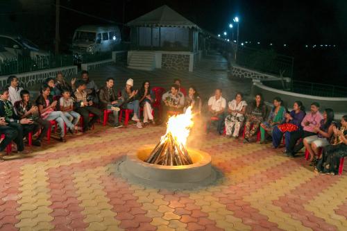 a group of people sitting around a fire pit at Relax Adventure Resort in Igatpuri