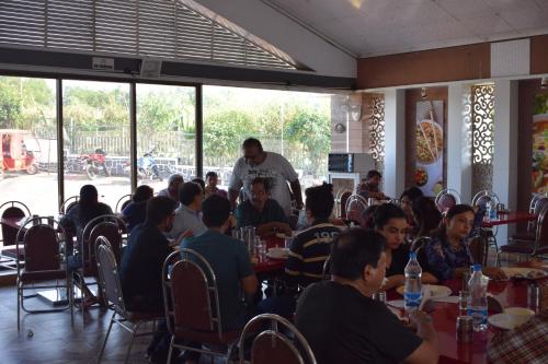 a group of people sitting at tables in a restaurant at Relax Adventure Resort in Igatpuri