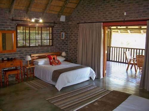 a bedroom with a bed and a desk and a balcony at Sunset Creek Game Lodge in Karino