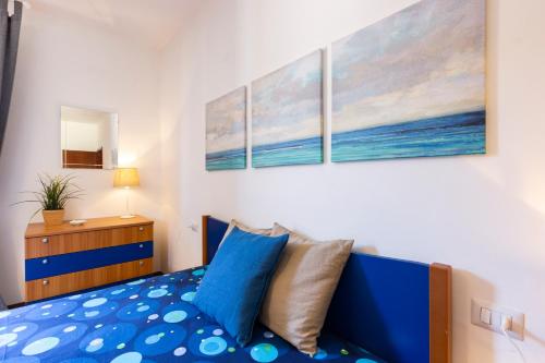 a bedroom with a blue bed and three paintings on the wall at Casa Donatella in Montecchio