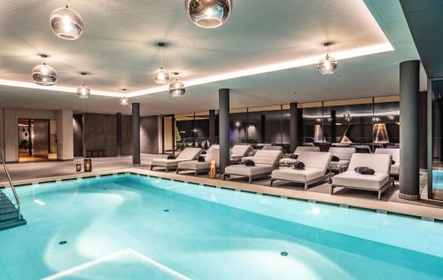 a pool in a hotel with lounge chairs and a swimming pool at Boutique Hotel Kircher in Sarntal