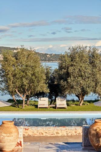 two white benches sitting in front of trees at 100 Rizes Seaside Resort- Small Luxury Hotels of the World in Gythio
