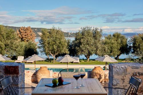 a table with two glasses of wine next to a pool at 100 Rizes Seaside Resort- Small Luxury Hotels of the World in Gythio