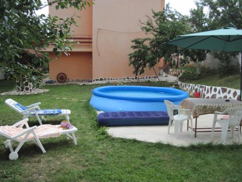einen Hinterhof mit Pool, Stühlen und Sonnenschirm in der Unterkunft Hadjibulevata Guest House in Kovachevtsi