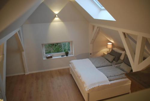 1 dormitorio en el ático con cama y ventana en Alte Korbflechterei en Hasselberg
