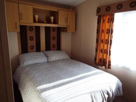 Habitación pequeña con cama y ventana en 3 Bedroom Caravan, en Tattershall