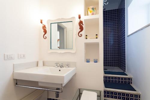 a white bathroom with a sink and a mirror at Casa Bellevue in Positano