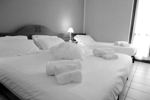 a bedroom with three white beds with towels on them at Hotel Ristorante Château in Aymavilles