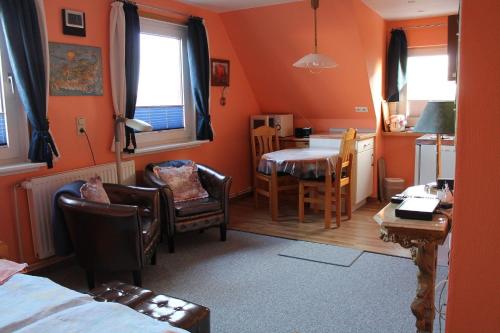 una camera con pareti arancioni e una cucina con tavolo e sedie di Googeswill-Wohnung-2 a Tinnum