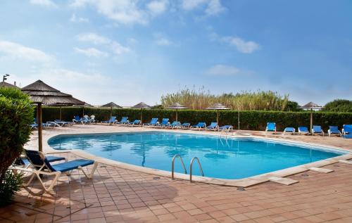 una gran piscina con sillas y sombrillas en TURIM Presidente Hotel en Portimão