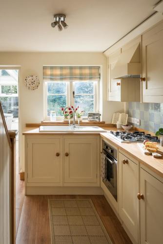 a kitchen with white cabinets and a sink at Old Fox Cottage in Evesham