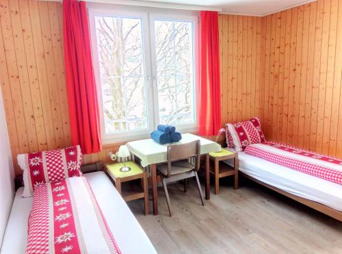 a room with two beds and a table and a window at Galluszentrum in Wildhaus