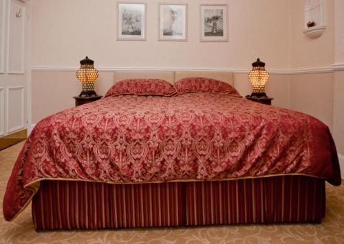 a bedroom with a red bed with two lamps at Hedley Villa Guest House in Leamington Spa