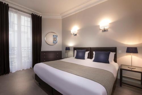 a bedroom with a large bed with blue pillows at Résidence Charles Floquet in Paris