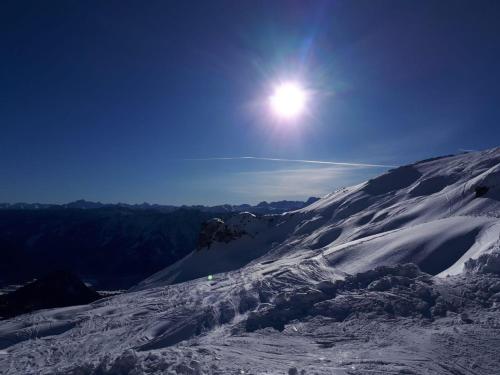 a snow covered mountain with the sun in the sky at Apartmenthaus Hinterer in Bad Goisern