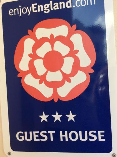 a sign for a guest house with a red and white flower at Hedley Villa Guest House in Leamington Spa
