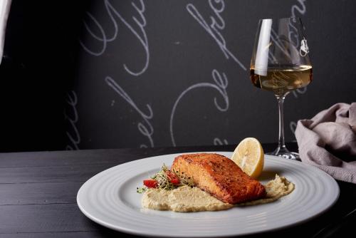 a white plate with a piece of chicken and a glass of wine at Weekend Boutique Hotel in Chişinău